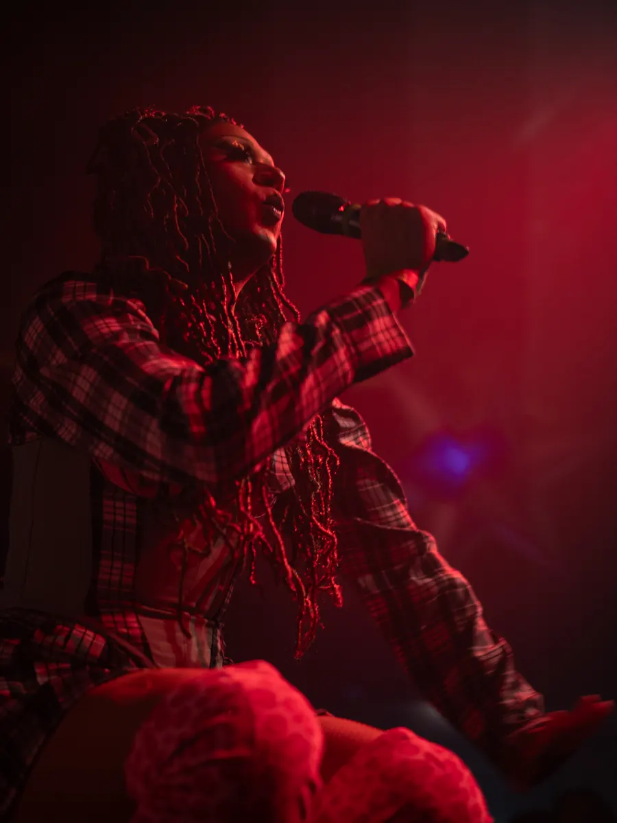 A performer singing on stage in red light