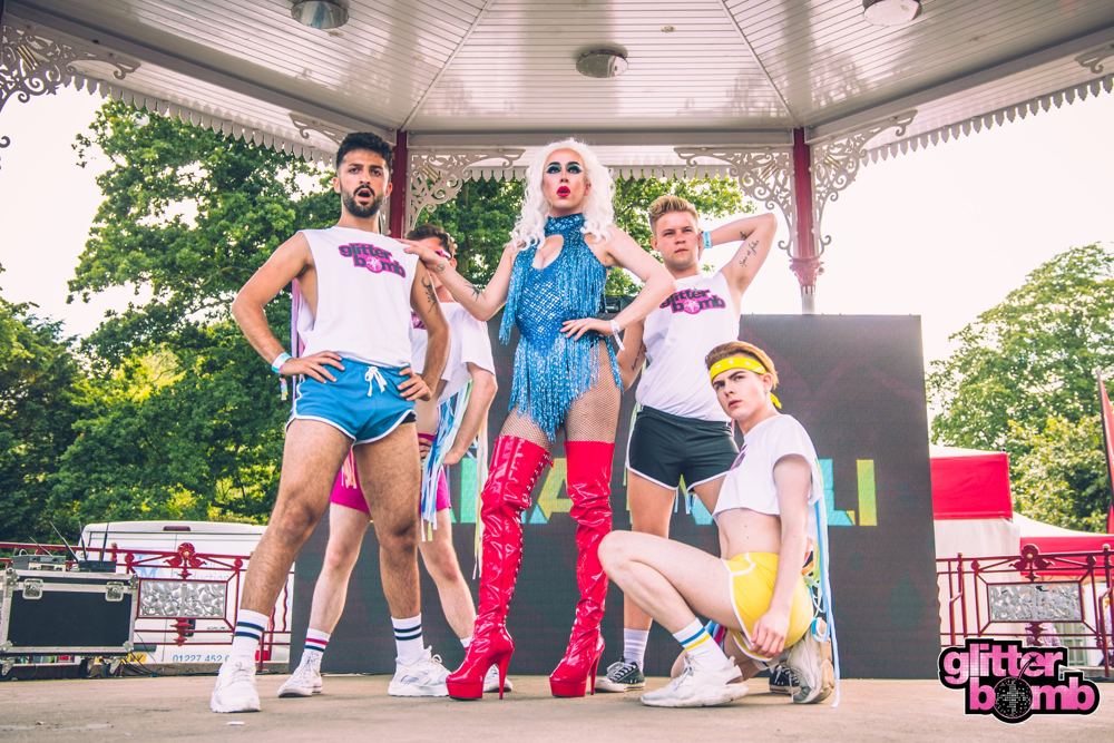 Performers on an outdoor Pride stage in daylight