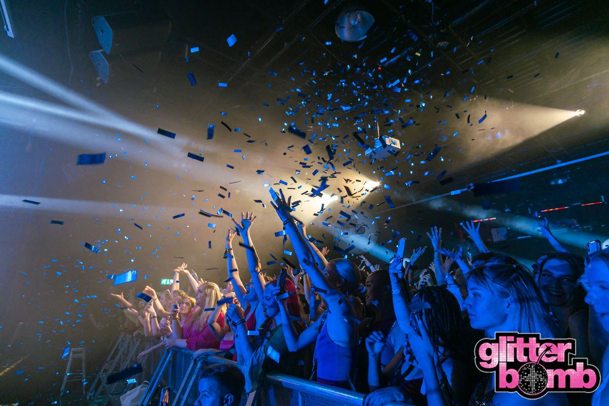 Confetti falling over a crowd with hands in the air at a Glitterbomb night